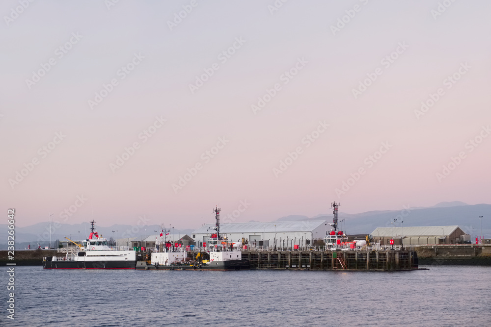 Shipbuilding port and ships at dock with crane at sunset coastal view