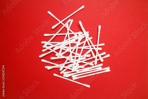 Cotton buds on a red background in the form of an art object for the beauty industry