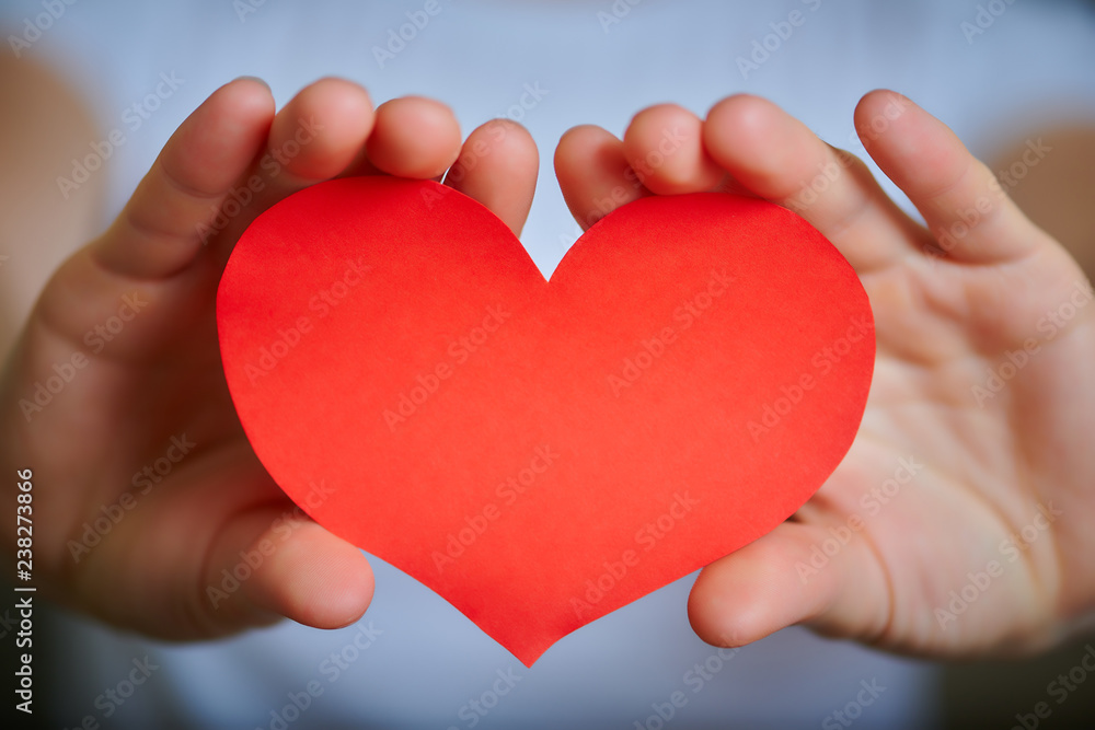Valentine's Day theme with red paper heart in young woman's hands, close-up Valentine's Day theme with red paper heart in young woman's hands, close-up