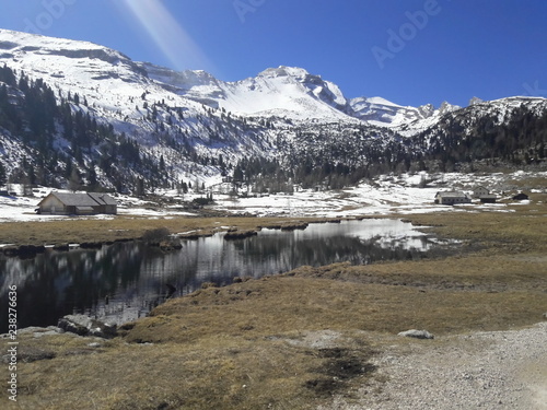 vallata alpi dolomiti con lago prato e montagne con neve sullo sfondo