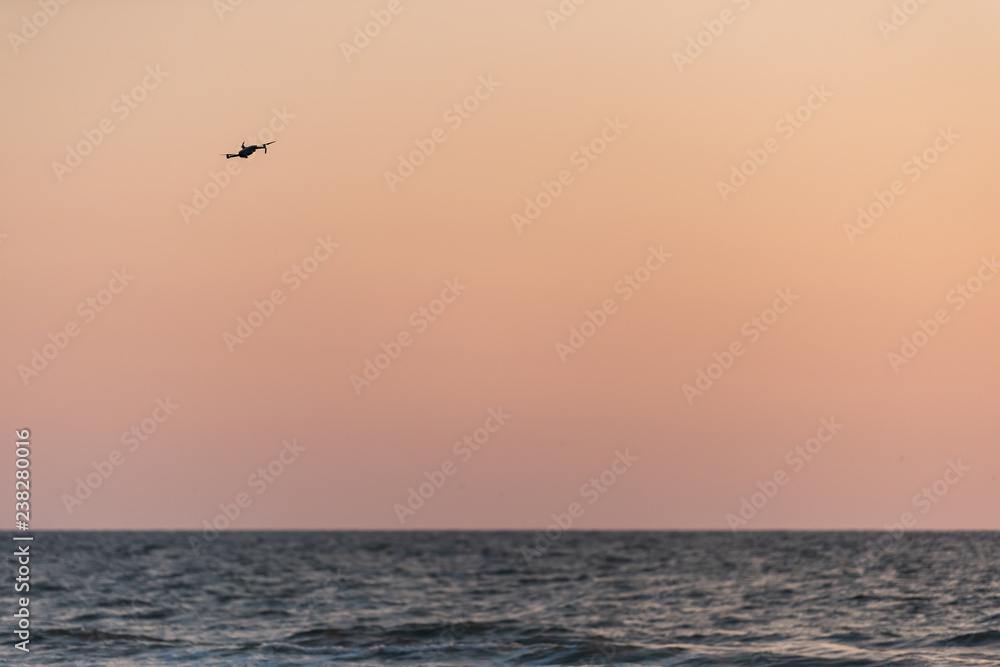 Naples, Florida red and orange sunset, one drone flying, in gulf of Mexico with nobody landscape, horizon, silhouette
