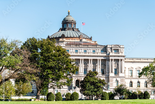 US National Library of Congress dome exterior with American flag waving in Washington DC, USA on Capital capitol hill, columns, facade landscape building architecture