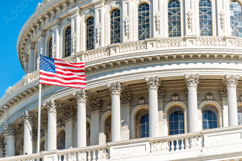 US Congress dome closeup with American flag waving in Washington DC, USA on Capital capitol hill, blue sky, columns, pillars, nobody photo