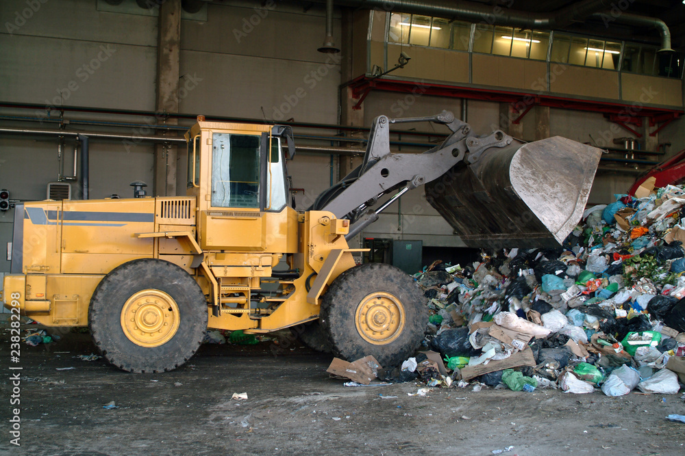 Fototapeta premium Bulldozer move pile of waste in a landfill.