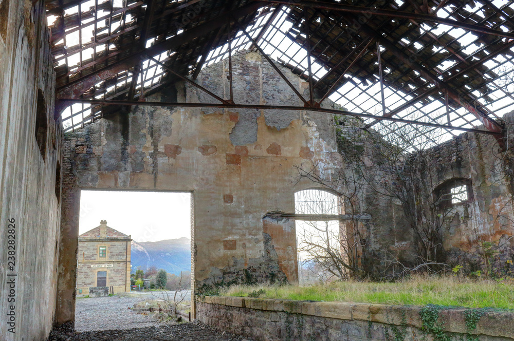 Abandoned train warehouse, with missing tiles from the roof, grass and ruined walls next to the railway in Santa Maria y La Peña train station, Spain Abandoned train warehouse, with missing tiles from the roof, grass and ruined walls next to the railway in Santa Maria y La Peña train station, Spain