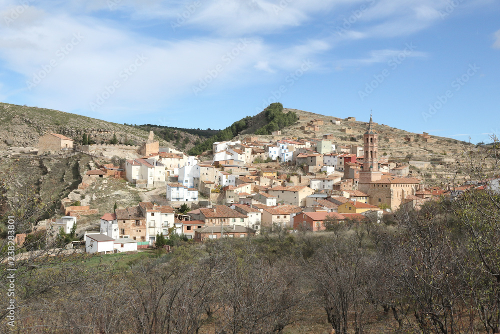 A landscape of the small rural town of Monterde, in the Aragon countryside, among hills and pastures, in a sunny autumn with bare trees, in Spain