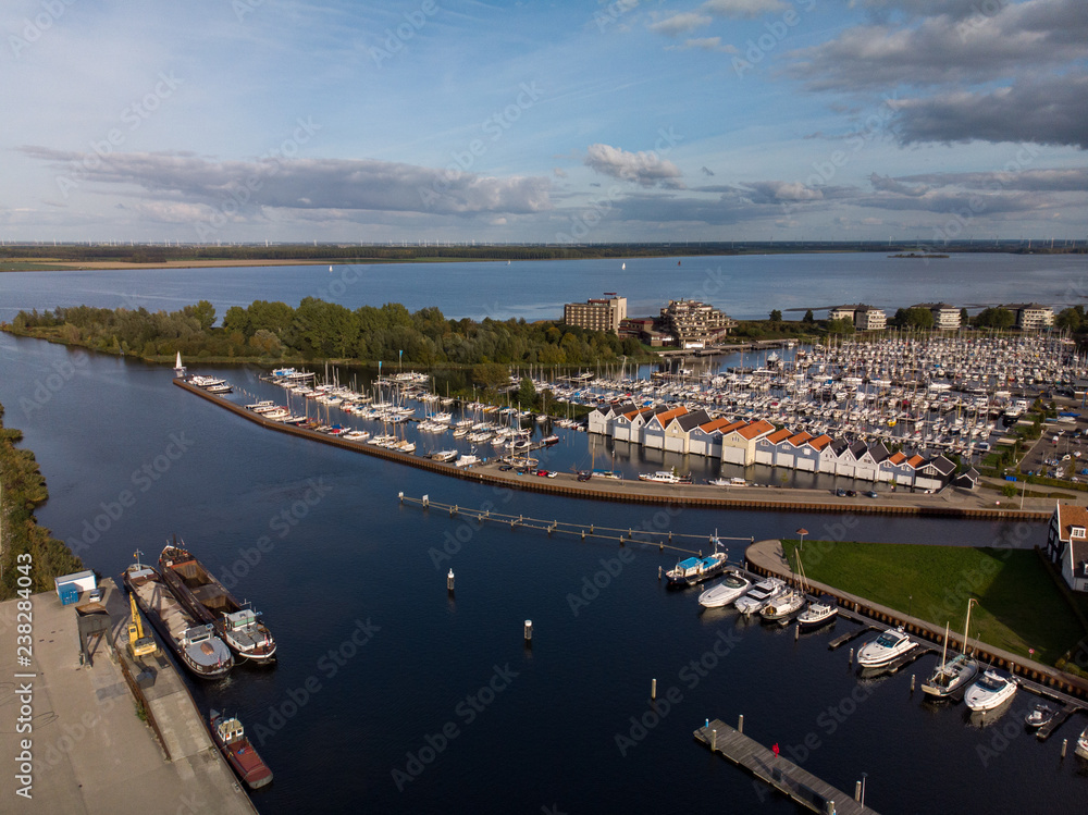 Aerial view of a recreational port with boats and boat houses with in the background a lake in The Netherlands