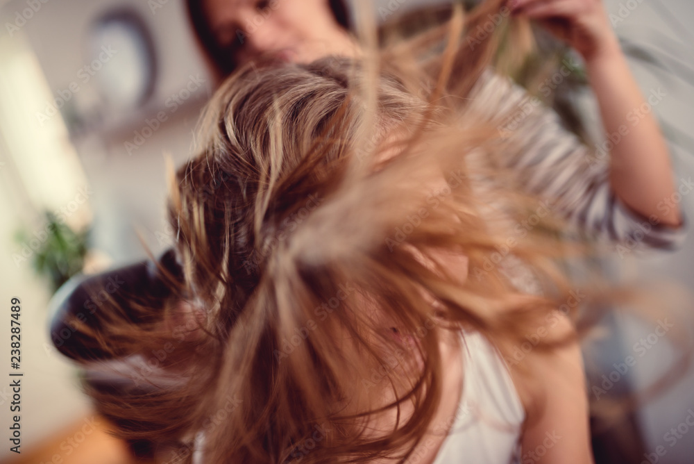 Fototapeta premium Mother drying hair to her daughter