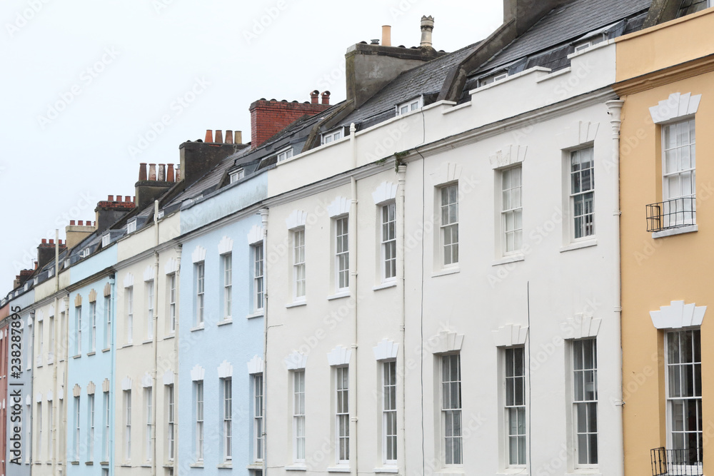 White, blue and rose terrace houses with sash hung windows, black roofs and chimney stacks in a cloudy day in Bristol, United Kingdom