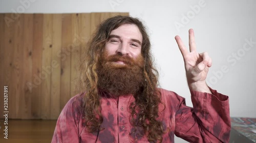 Long haired hipster hippie type man solo indoors giving peace sign