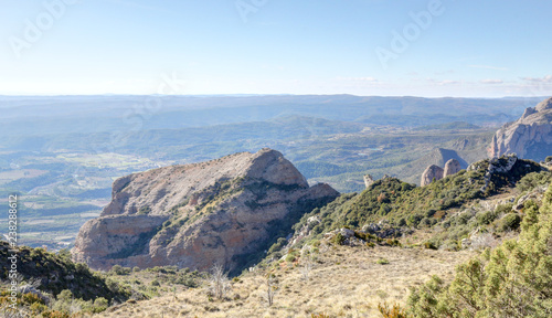 A landscape of the pre-Pyrenees lands, with rocks and fir and pine tree forests in the Mallos de Riglos mountain peaks during winter in Aragon, Spain