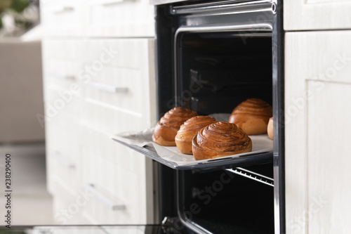 Open oven with tray of freshly baked buns in kitchen