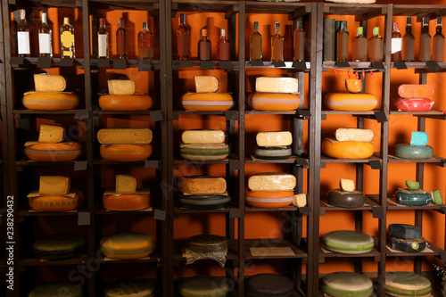 Different types of delicious cheeses and alcohol drinks on rack in store