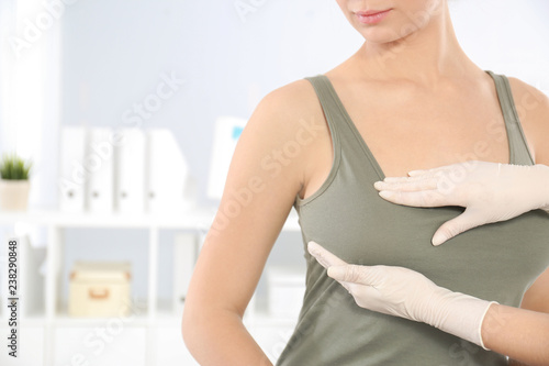 Doctor checking woman's breast at hospital, closeup. Space for text photo