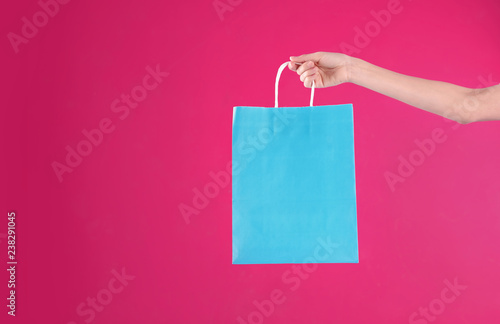 Woman holding shopping bag on color background, closeup. Mock-up for design