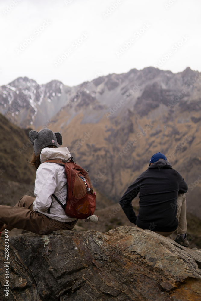 two hikers sitting on rock in mountains