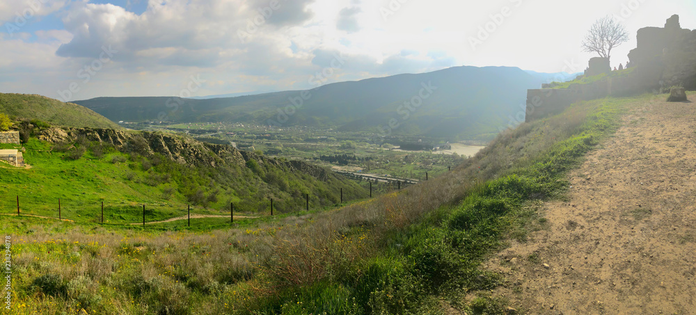 Ruins of an old fortress against the sky, panoramic view. Spring, green fields