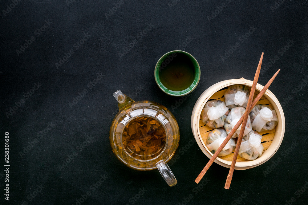 Dinner in Chinese restaurant with dim sum, sticks and herbal tea on black background top view space for text Dinner in Chinese restaurant with dim sum, sticks and herbal tea on black background top view space for text