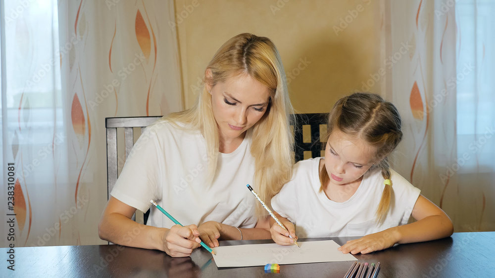 Beautiful adult woman and girl painting with pencils on paper sitting at table at home Beautiful adult woman and girl painting with pencils on paper sitting at table at home