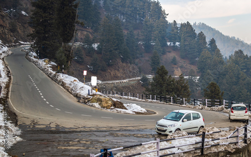 Gulmarg, Jammu and Kashmir, India: Date- November 15, 2018- Snow along the sides of curvy roads on hilly terrain with cars parked