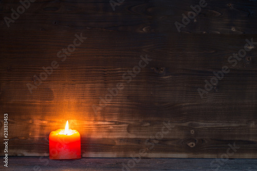 Burning candle on old wooden background