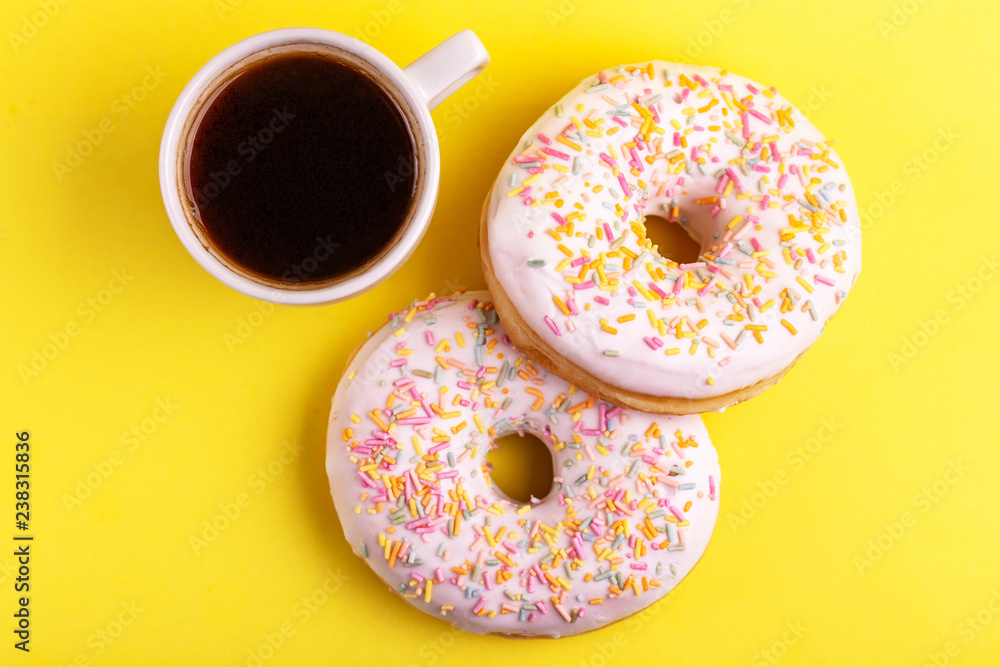 Two delicious vanilla donuts with sprinkle and cup of coffee Two delicious vanilla donuts with sprinkle and cup of coffee