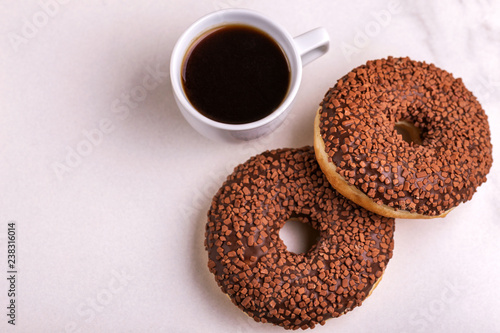 Two delicious chocolate donuts with sprinkle and cup of coffee