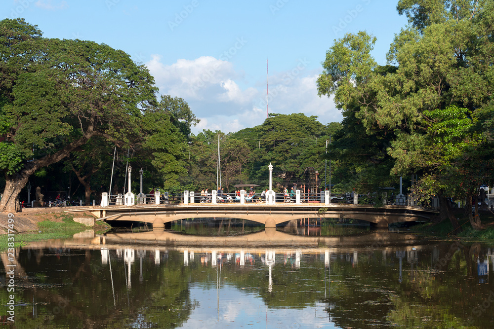 A bridge in Siem Reap in the middle of professional traffic with reflections in the river, Cambodia