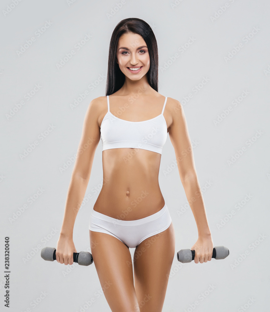 Fit and beautiful woman in swimsuit. Sporty girl with dumbbells. Fitness, diet and healthy lifestyle concept. Fit and beautiful woman in swimsuit. Sporty girl with dumbbells. Fitness, diet and healthy lifestyle concept.