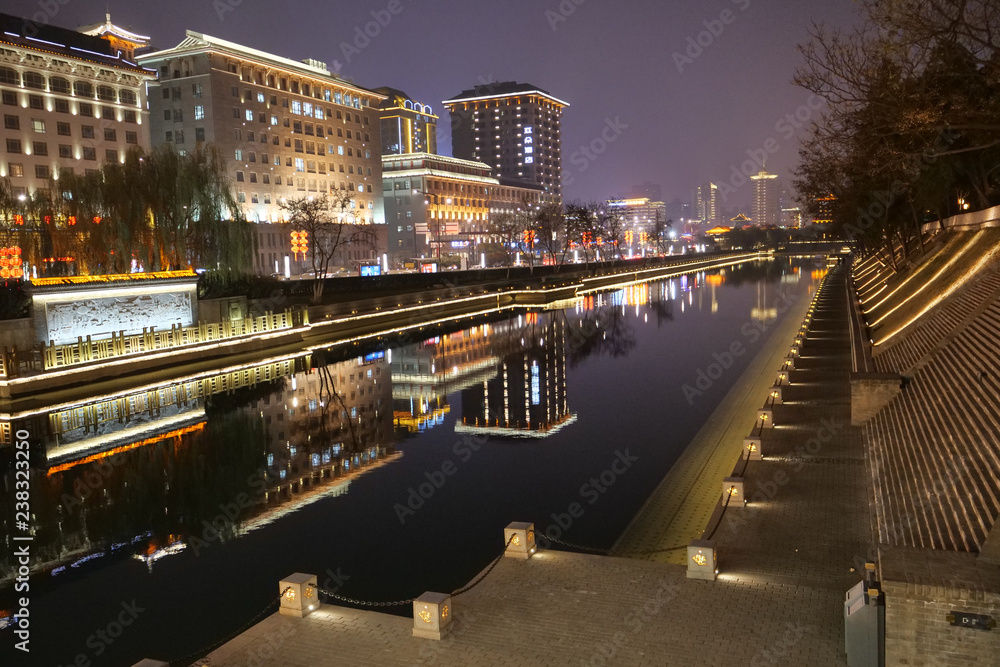 Ancient Asia city moat with reflections of modern buildings at night