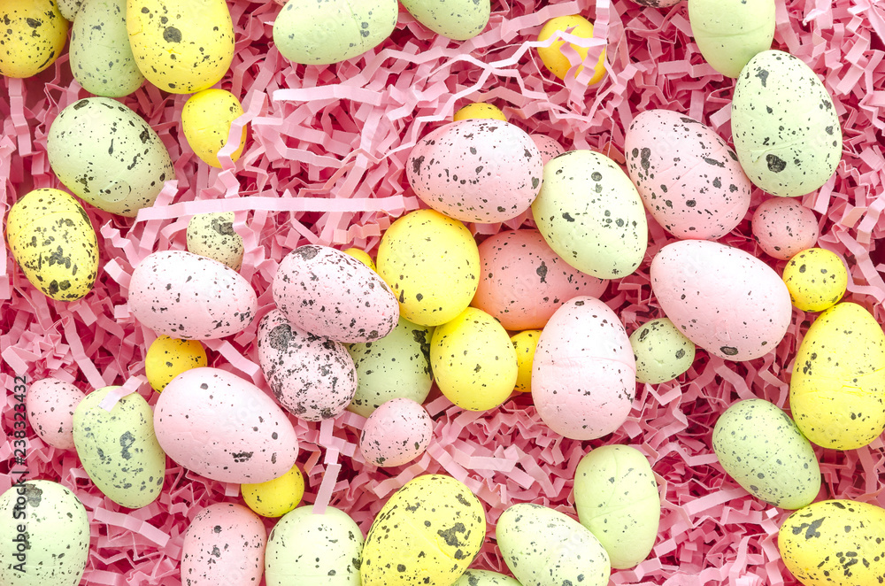 Colorful Easter eggs in paper filler, top view. Easter background flat lay.Greeting card pink color
