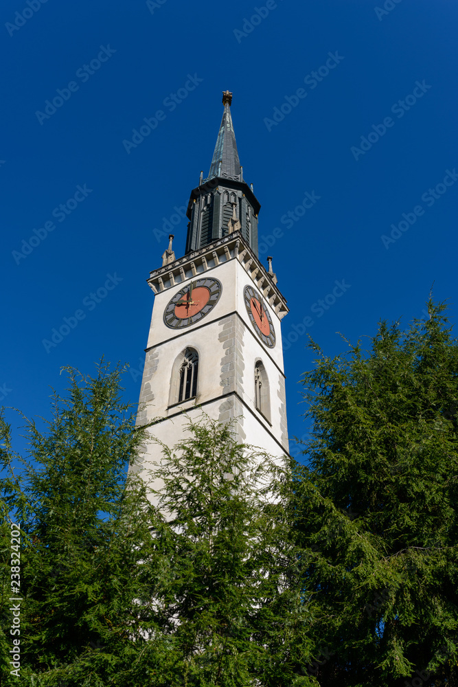 Close-up of the bell tower of Saint Jacob cathedral church kirche in Cham town (Zug, Switzerland) on the clear blue sky background on a summer day