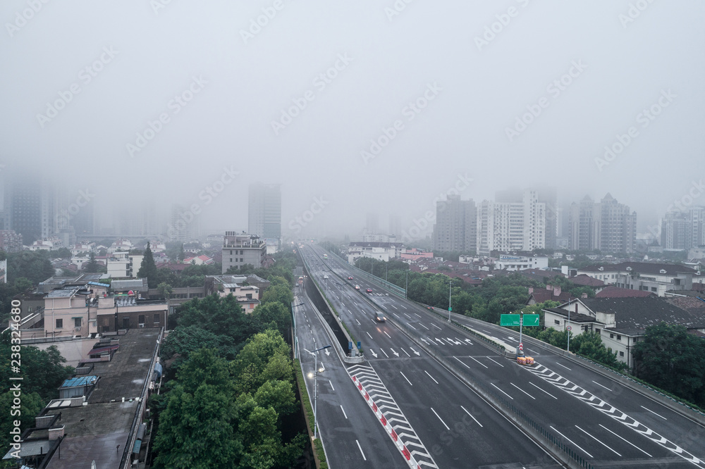 Aerial view of buildings and highway in the morning fog