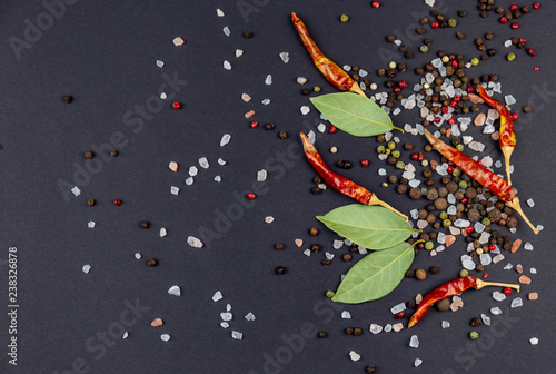 Black background whith chilli, salt, pepper and laurel