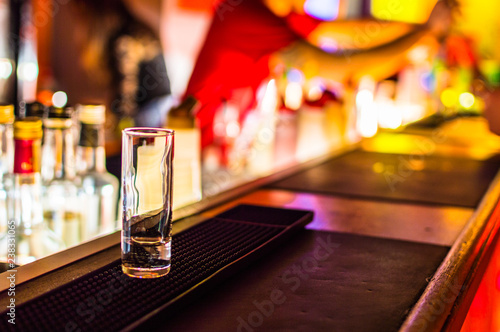 colored and beautiful Chupito drink with bokeh blurred background of an animated and illuminated pub with people moving behind