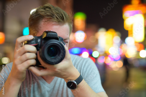 Face of young tourist man photographing with camera in the streets of Chinatown at night