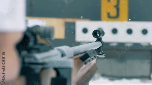 Snowfall and close up of rifle's barrel during aiming process photo