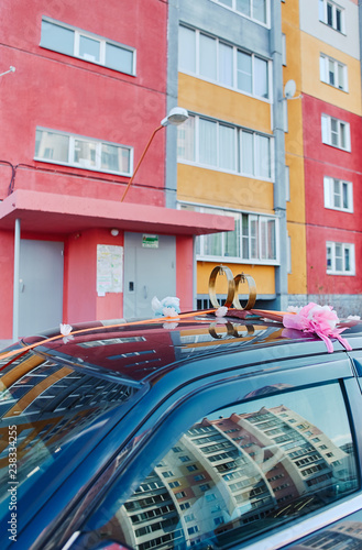 Wedding rings with bells on the roof of the car, against the background of urban buildings. Traditional Russian decoration of a wedding convoy.