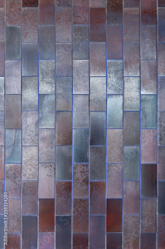 vertical wall lined with ceramic tiles of different colors close up