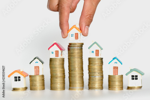 Woman hand hold a home model put on the stack coin with growing, Savings money for buy house and loan to business investment for real estate concept.