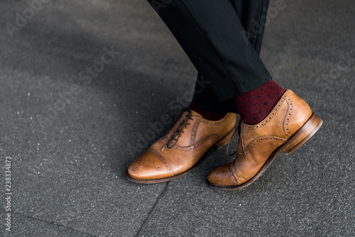 cropped view of male crossed legs in burgundy socks and oxford shoes