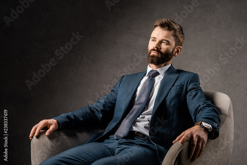 confident bearded businessman resting in armchair