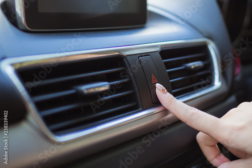 Close up finger hitting car emergency light botton in car.