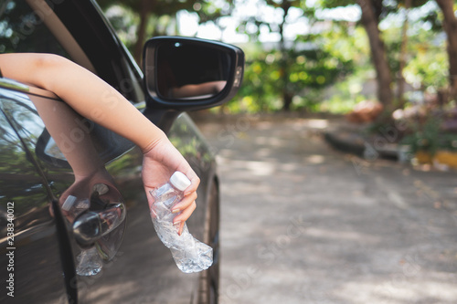 Hand throwing plastic bottle on the road.