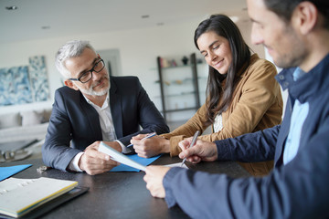  Attractive couple signing contract with real-estate agent in contemporary house