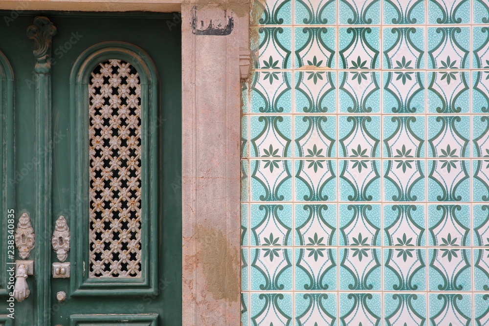 Close-up of a typical entrance door surrounded by patterned tiles (azulejos) inside the old town of Tavira, Algarve, Portugal