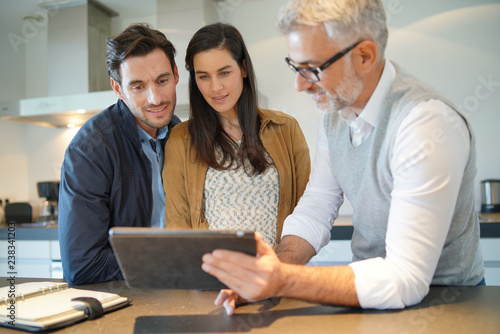 Fotografie Kitchen salesman going through ideas with potential buyer couple
