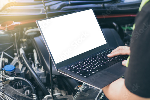 Close up engineer  mechanic using electrnoic diagnostic equipment to tune a car, Laptop blank screen.. photo