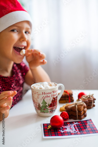 Wallpaper Mural Little girl in Santa hat eating marshmallow from mug with cacao and cookies, Merry Cristmas Torontodigital.ca
