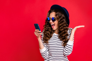 Portrait of nice funny lovely attractive cheerful positive wavy-haired lady in striped pullover eyeglasses eyewear sunhat reading sms opened mouth isolated over bright vivid shine red background